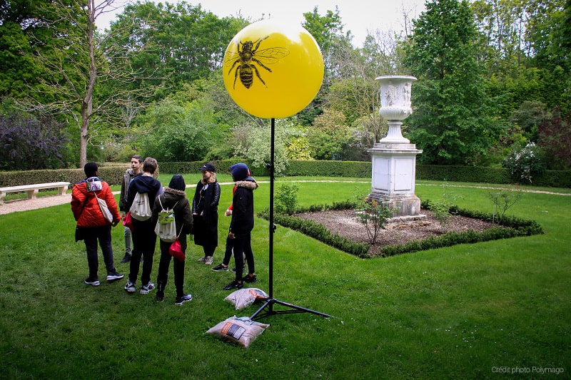 Des collégiens au château de Versailles devant un ballon sur trépieds jaune de 80cm